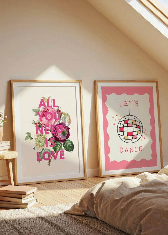 Two framed prints on a wall in a room with books and bedding. all you need is love floral print and hand drawn lets dance disco ball print
