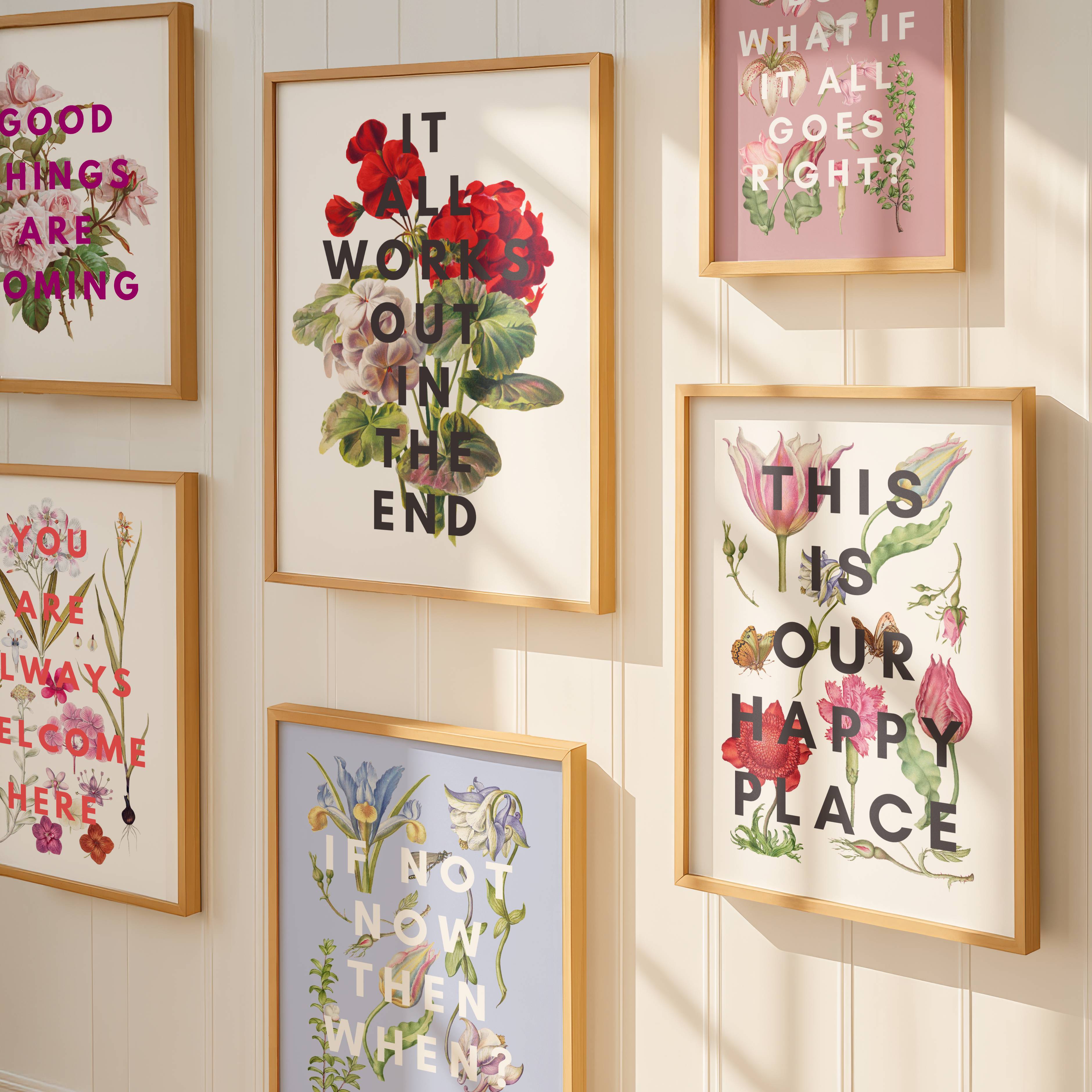 Decorative wall art prints with motivational phrases and floral designs on a light wooden panel.