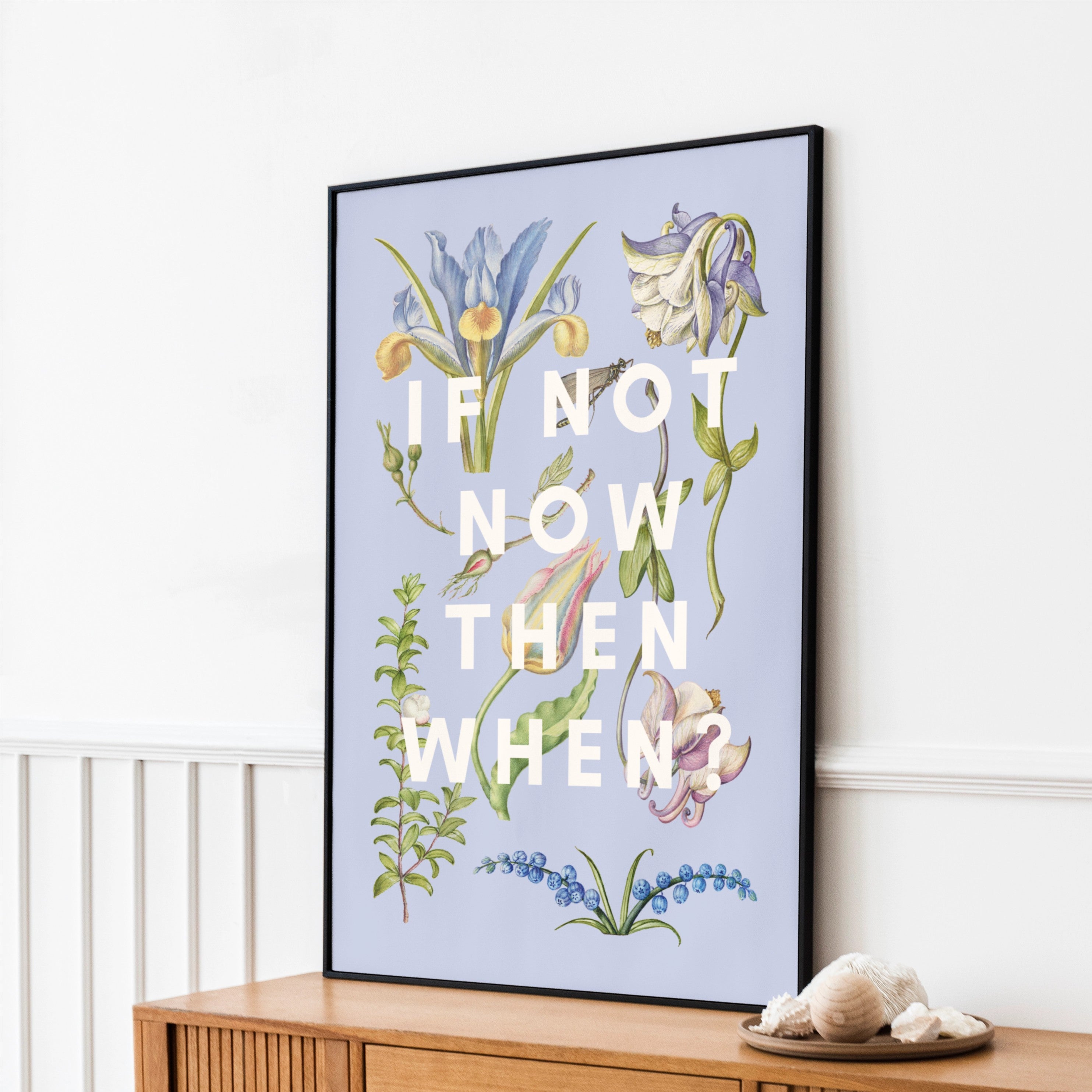 Framed botanical art print with motivational quote on a wall above a wooden cabinet.