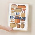 Framed poster of various types of cheese with 'LE FROMAGE' text on a beige wall.