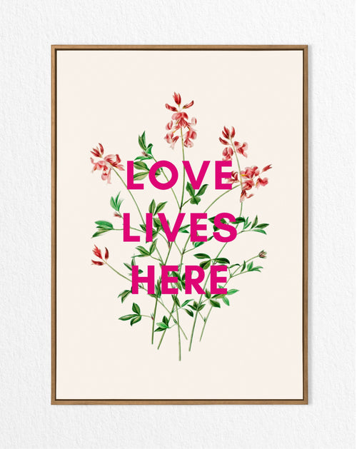 A framed art print with a vintage floral design and the text 'LOVE LIVES HERE' in bold letters.