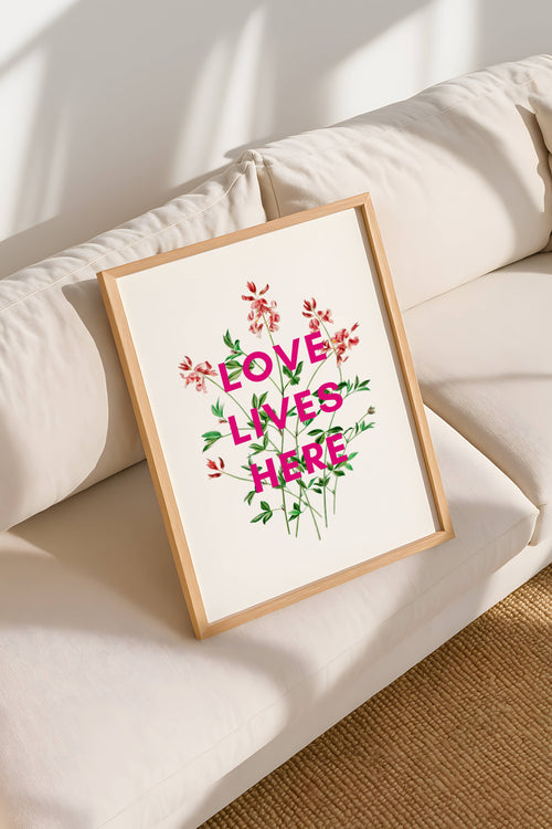 Framed artwork with 'Love Lives Here' text on a white surface