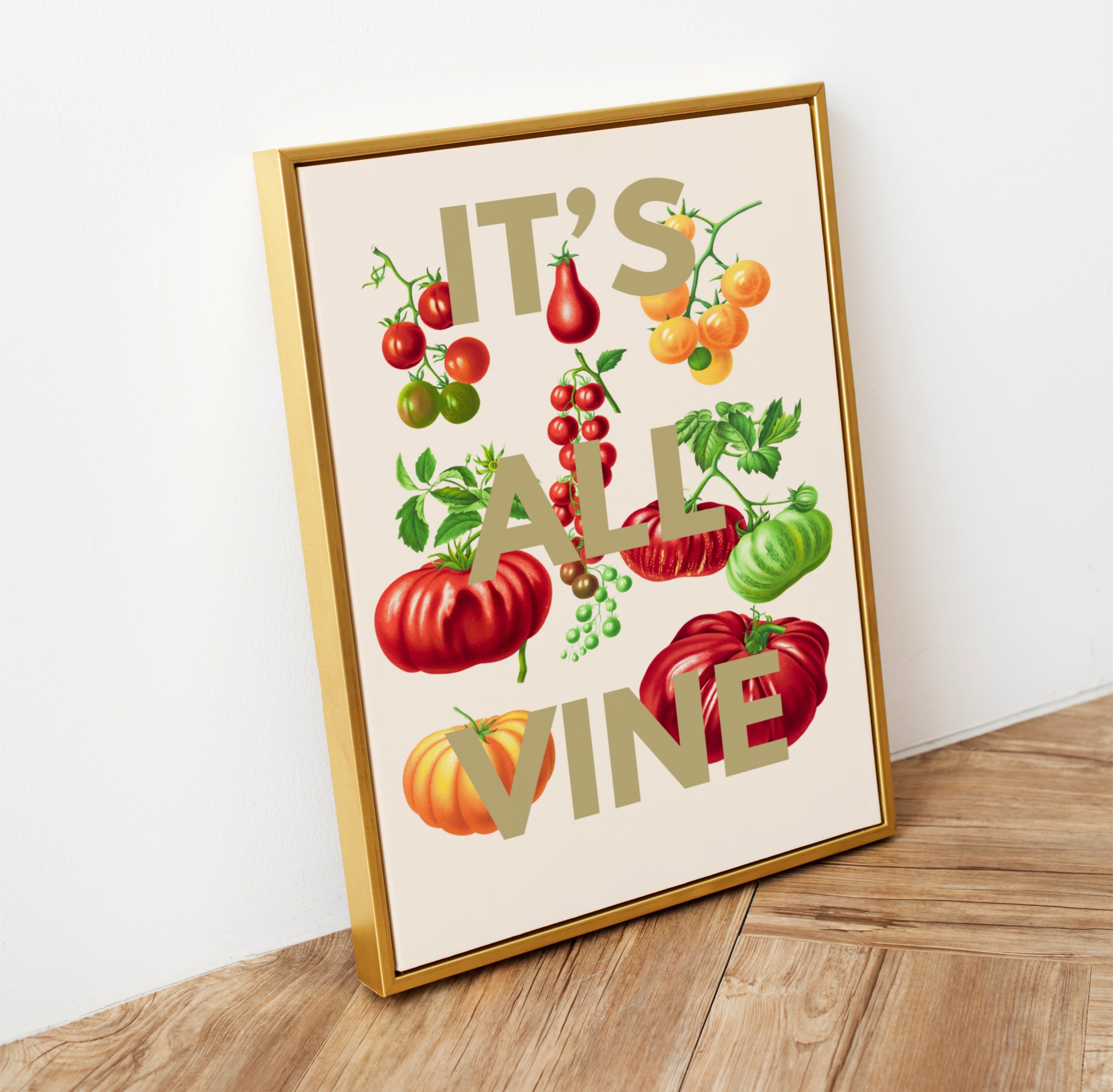 Framed artwork with colourful fruits and vegetables and text 'IT'S ALL VINE' on a wooden surface.
