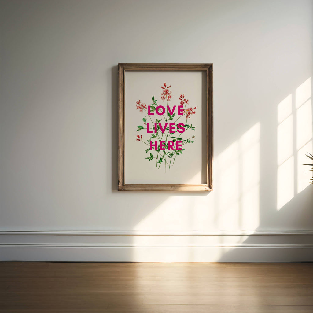 Framed artwork with 'Love Lives Here' text and floral design on a wall.